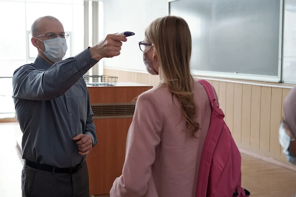 Łysy dojrzały mężczyzna mierzący temperaturę młodej studentki