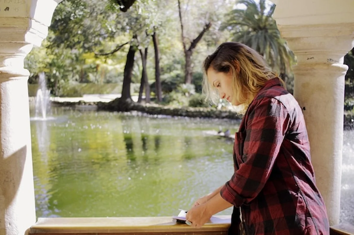 Kobieta pisząca pamiętnik na balkonie przy stawie