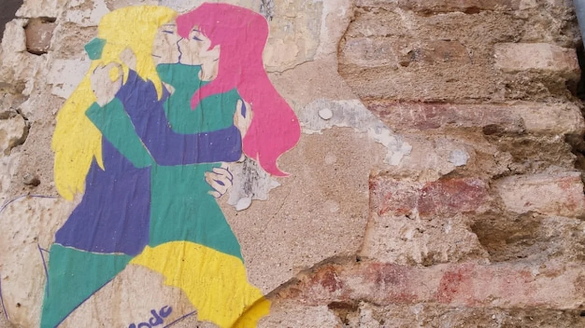 Mural lesbijskiej pary całującej się na zniszczonej ścianie