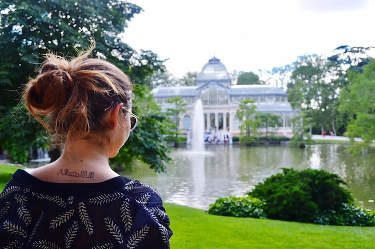 Kobieta stojąca przed jeziorem i budynkiem