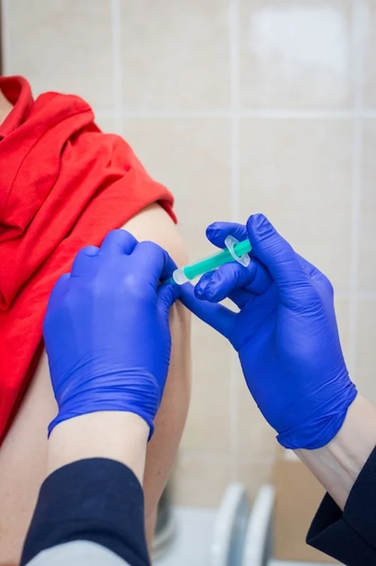 Lekarz wykonuje szczepienie w ramię pacjenta w szpitalu