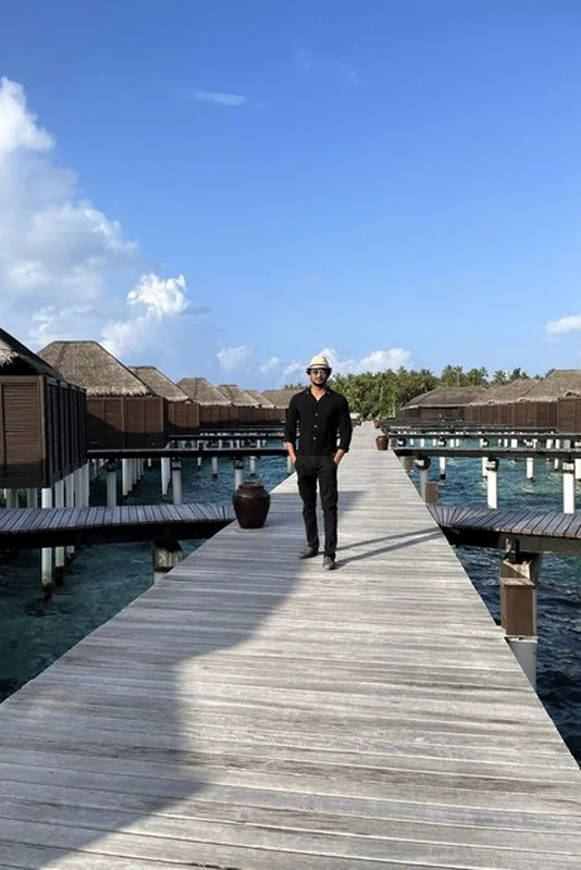 Mężczyzna w czarnej odzieży na drewnianym molo na Malediwach