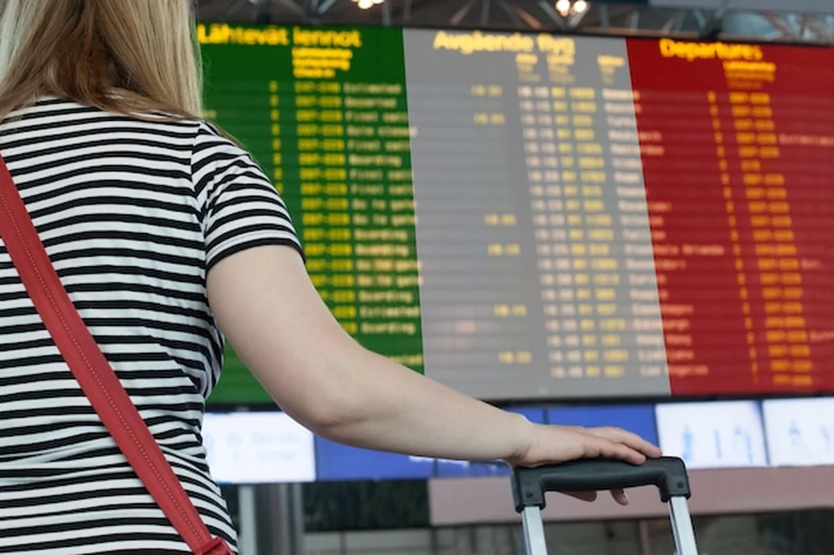 Kobieta patrzy na tablicę wyników na lotnisku