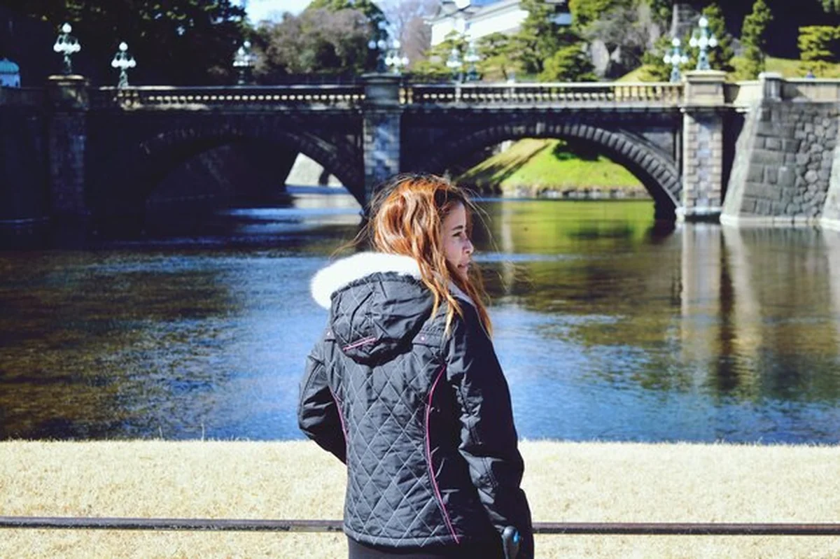 Kobieta stojąca przy rzece przy moście