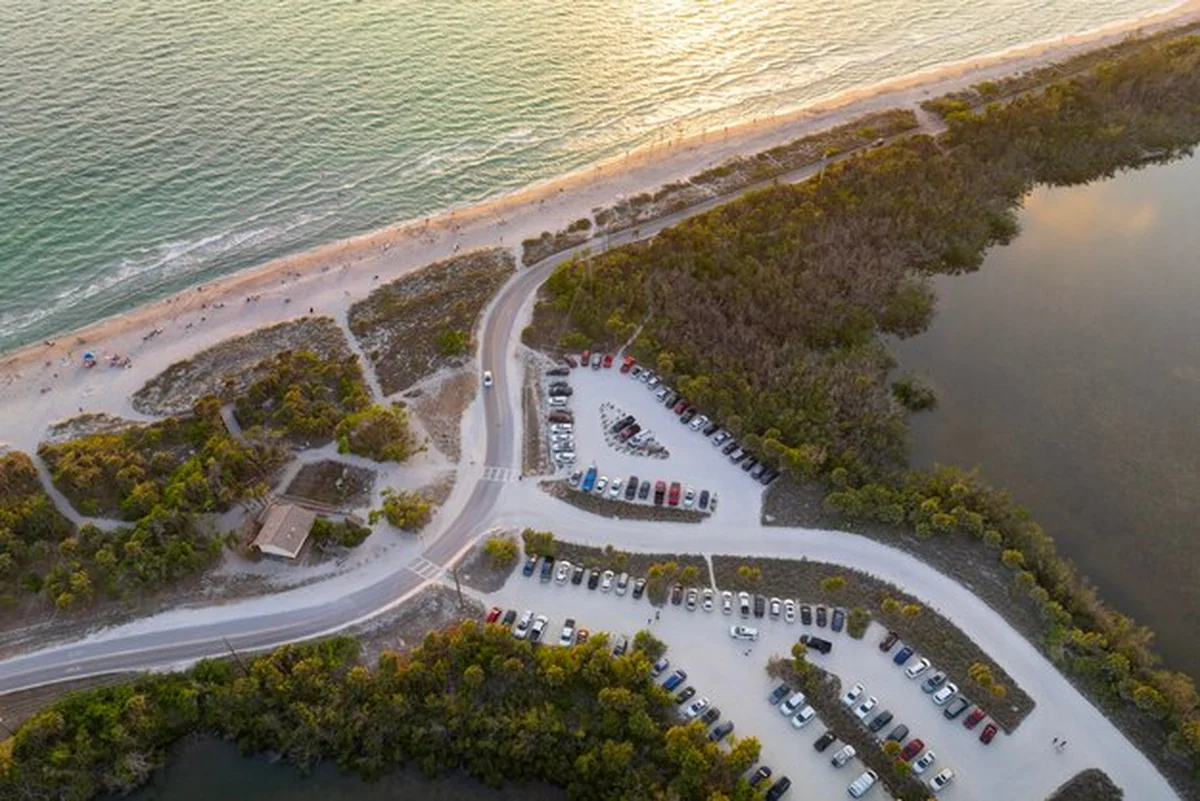 Parking dla samochodów turystów przy plaży oceanicznej z białym piaskiem na Florydzie o zachodzie słońca