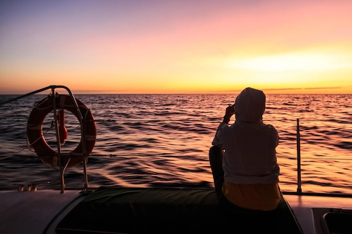 Kobieta na łodzi na morzu podczas zachodu słońca