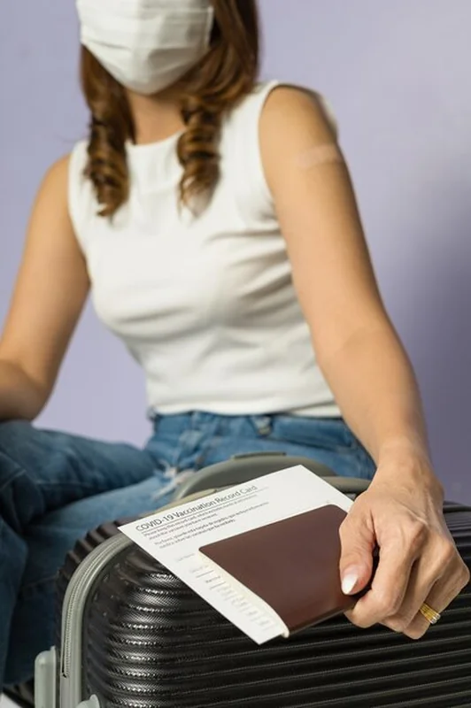 Kobieta zaszczepiona i trzymająca dokumenty podróżne