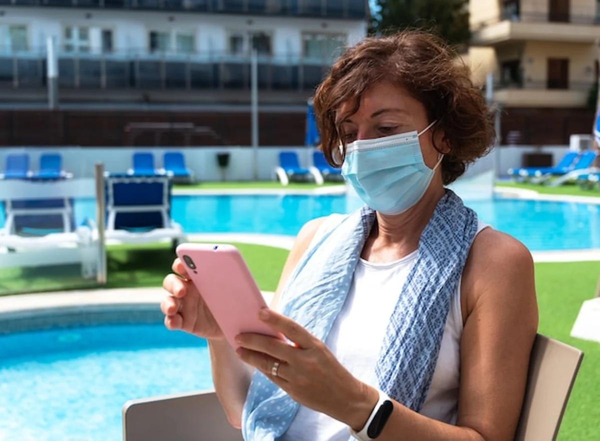 Kobieta z maską chirurgiczną rozmawia przez telefon komórkowy