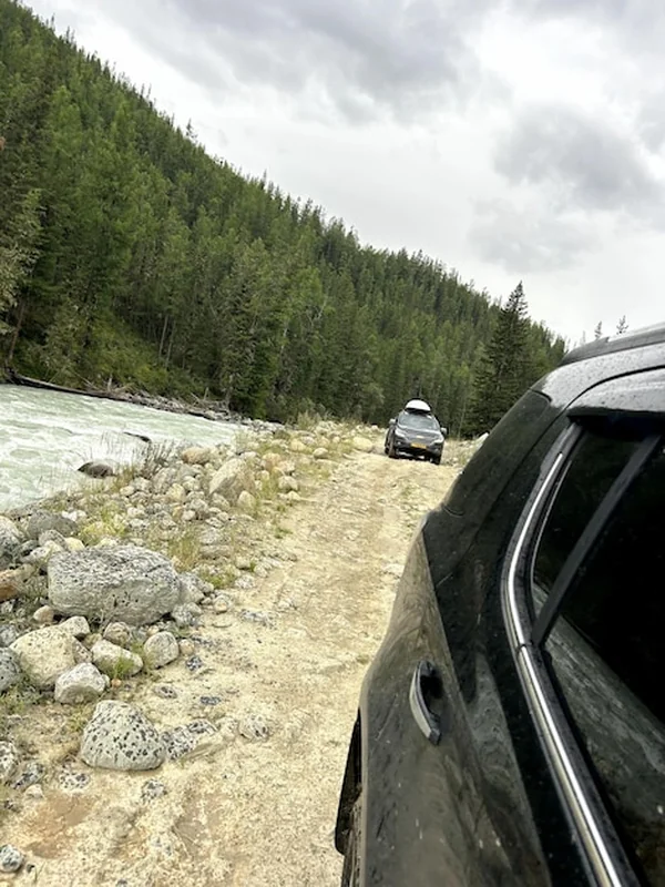 Samochód jeździ obok rzeki po ziemianej drodze